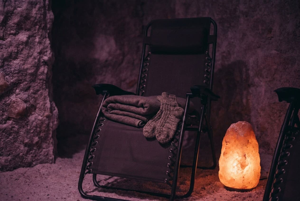 Warme Socken und eine Decke auf dem Liegestuhl neben einer Salzlampe